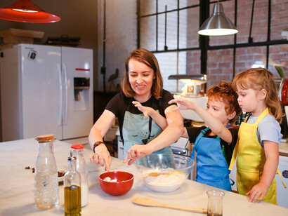 A mother and children cooking in the kitchen, enjoying family time and learning together