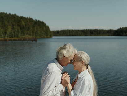An elderly couple embraces lovingly by the lake, radiating joy and connection