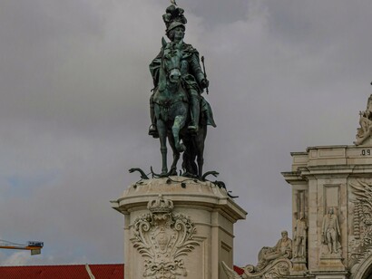 Estátua Do Rei José I Na Praça Do Comércio, Lisboa, Portugal. Cidades como Lisboa e Porto estão a ser fortemente impactadas pela especulação imobiliária, com os preços das casas a subir a níveis insustentáveis. A promessa de um turismo sustentável parece cada vez mais distante, dado que o setor depende, em grande parte, de mão-de-obra temporária e mal paga. A solução talvez passe por olhar para regiões menos densamente povoadas, onde há mais espaço para um desenvolvimento mais equilibrado