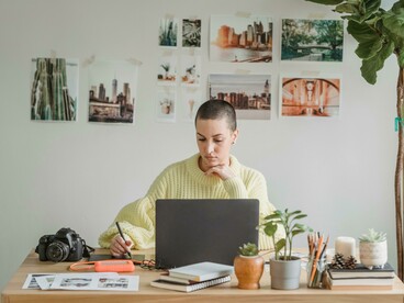 A woman works on her laptop while sketching on a drawing tablet, capturing the flow of a graphic designer at work