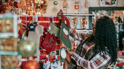 A smiling Black woman choosing Christmas decorations in a store