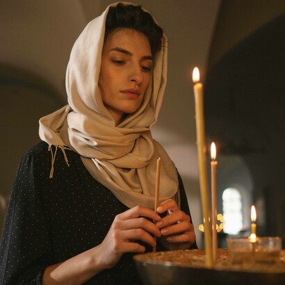 Una donna con uno scialle tiene una candela in mano, durante una pratica cultuale