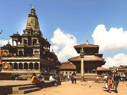 Tourists explore the facade of a Buddhist temple in Patan, Nepal