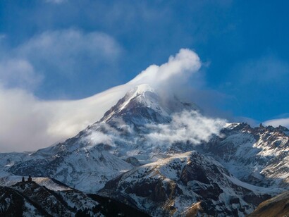 La cima isolata tra le nuvole innevate sembra custodire un segreto antico: che nella solitudine e nel silenzio si può percepire la vastità della vita in modo più puro