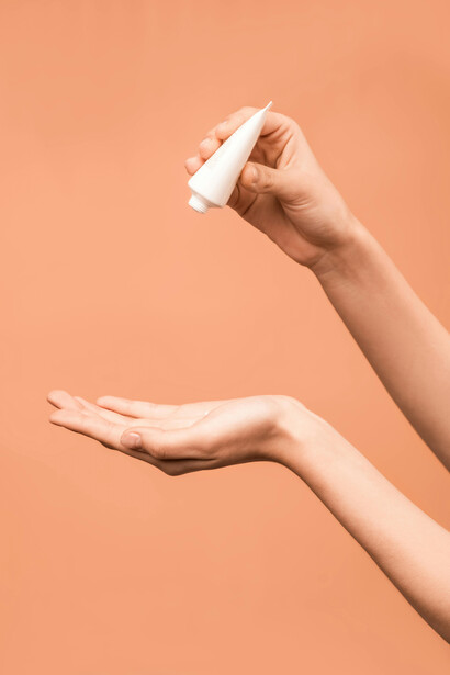 Person holding a white plastic tube of sunscreen for skincare