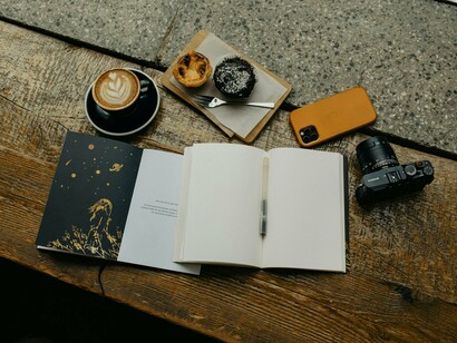 A table holding books, food and camera, illustrating a diverse range of interests and hobbies for any well-rounded individual who values both intellectual pursuits and creative expression  