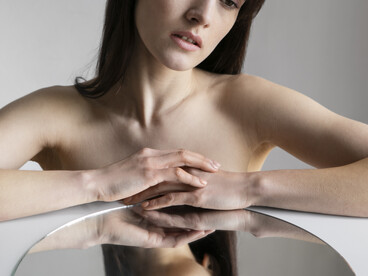 Ritratto frontale di donna con il riflesso capovolto del viso su uno specchio rotondo