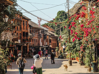 A group of people walking near concrete buildings in Bandipur, Nepal, during the daytime