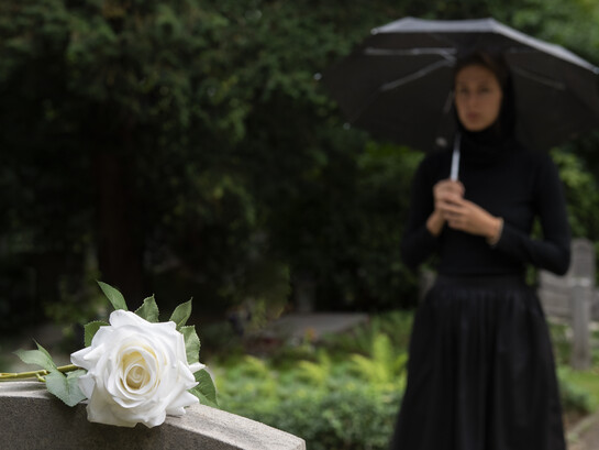 A young woman in a graveyard holding a white rose