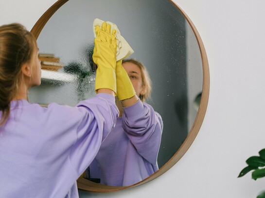 Une femme nettoyant un miroir soigneusement et se concentrant sur la tâche