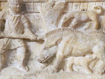 Il cinghiale, anziché incarnare una minaccia cieca, si rivela una creatura cosciente e parlante, capace di osservare e giudicare il comportamento umano. Urnette in alabastro di produzione volterrana con caccia al cinghiale, del 110 a. C. 