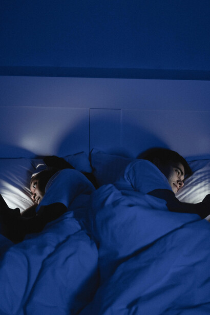 A couple in bed, illuminated only by their phone screens