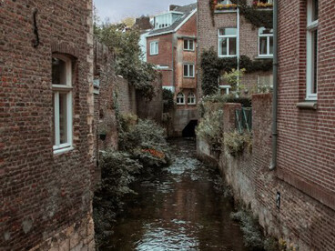 By the calm river in Maastricht, a brown brick building rests among quiet houses and timeworn facades, echoing the charm of the Netherlands