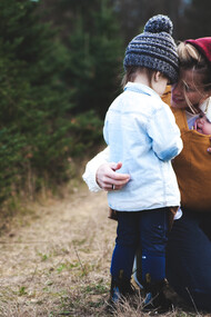 Una madre con sus hijos en la vereda de un bosque
