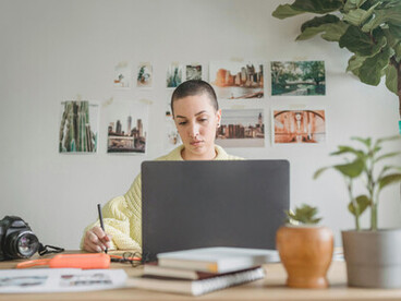 Graphic designer at computer a woman blends digital tools on laptop and tablet to create artwork