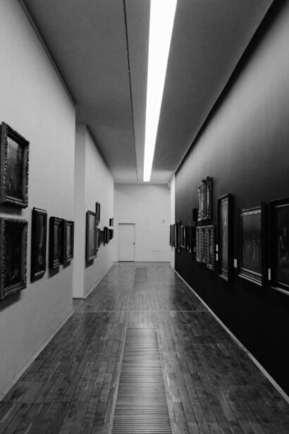 A black and white photograph of an empty art gallery, quiet and still