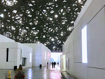 Les visiteurs explorent les galeries du Louvre Abu Dhabi, baignées par la lumière filtrée du dôme métallique qui suspend l’art entre ciel et mer