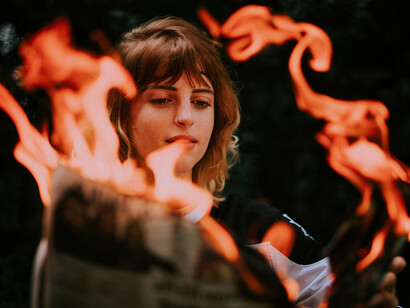 A girl plays with fire, setting a newspaper ablaze—a powerful metaphor for confronting disinformation