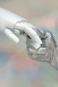 A gloved hand holding a robotic hand 