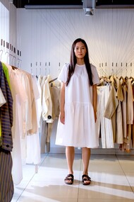 Mulher com vestido branco e sandálias em brechó