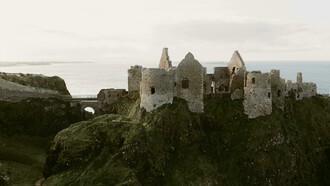 Ruínas medievais do Castelo Dunluce na costa do oceano na Irlanda do Norte, no Reino Unido. Ao final destes dias intensos e cheios de descoberta, regressámos com a sensação de ter conhecido uma Irlanda rica em contrastes — da tranquilidade de vilas junto a lagos às falésias imponentes, das paisagens verdes e rurais às cidades marcadas pela história e pela cultura, bem como pela presença ainda visível da divisão entre a Irlanda Católica e a Irlanda Protestante