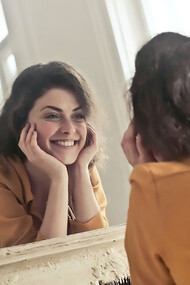 Happy and positive woman looking in the mirror