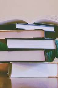 Boy covered up by a pile of books, sometimes the stress of having to study for exams or tests comes up