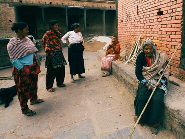 A group of homeless women resting beside an unfinished building, representing the human cost of housing systems that exclude the most vulnerable