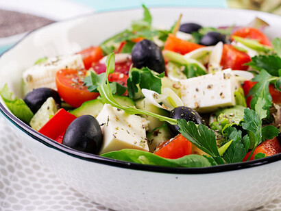 A Greek salad featuring cucumber, tomato, sweet pepper, lettuce, green onion, feta cheese, and olives, all drizzled with olive oil – a vibrant, nutrient-packed dish that supports brain health and embodies the principles of the Mediterranean diet