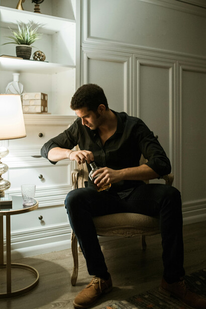 A man lounges on the sofa, bottle in hand, caught in the grip of habit