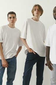 Men posing in classic white T-shirts and jeans against a minimalist backdrop