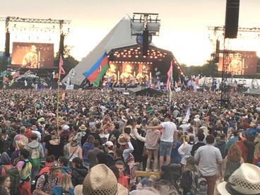 A vibrant crowd standing before the stage at Glastonbury Festival in England, capturing the spirit of music and togetherness