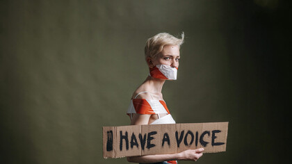 A woman holds a placard that reads “I have a voice”