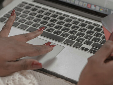 A woman typing her card information on a laptop, reflecting the impulse to shop online as a response to emotional loneliness and the search for fulfillment