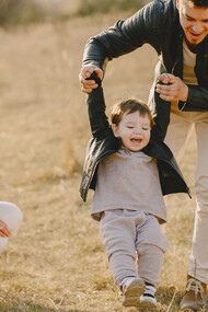Mãe e pai levam o filho para brincar no campo de forma que aproveitem uma paisagem mais natural e ar puro