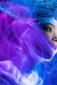 A woman with striking blue eyes illuminated by soft blue string lights