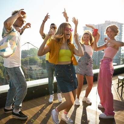 Young consumers dancing at a rooftop party, symbolizing the lively engagement brands aim for during product launches. Such events create memorable rituals, fostering a deeper connection between brands and their audiences
