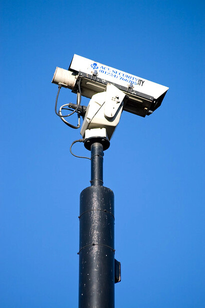 A CCTV camera silhouetted against the blue sky, highlighting the rise of facial recognition technology