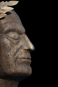 A bronze bust of Julius Caesar facing the dark