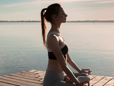An athletic woman engages in meditative stretches on the beach