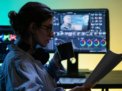 A woman sits on a chair surrounded by computer screens, reflecting digital overload, information saturation, and the constant multitasking of modern technology