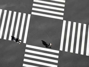 Silhouettes of people standing at a crossroads in a city
