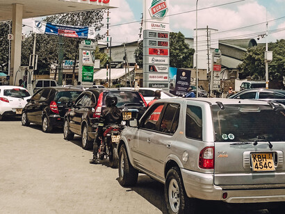 Une longue file de voitures s’étire dans une station d’essence, symbole de l’impact direct du blocus des importations sur la vie urbaine et l’économie locale