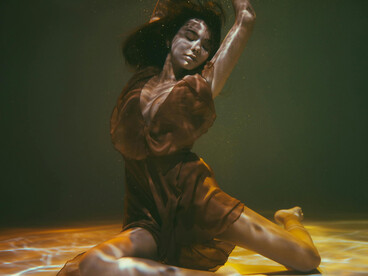 Woman floating underwater in a flowing dress