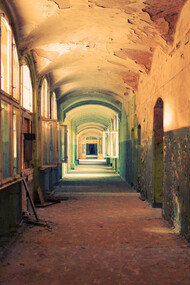 A deserted indoor hallway in a ruined, deteriorating house
