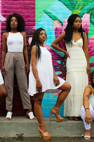 Six African American women dressed in white pants pose together in the USA