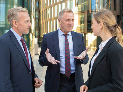 A group of bankers in office attire holding an outdoor meeting to discuss strategies during a banking crisis