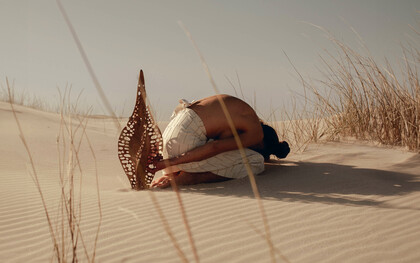 A shared reverence, Karlien folding into the dunes beside ‘Diatom Bokeh’ from the Epiphanic series collaboration with Reticence Studio, photographed by Driaan Claassen