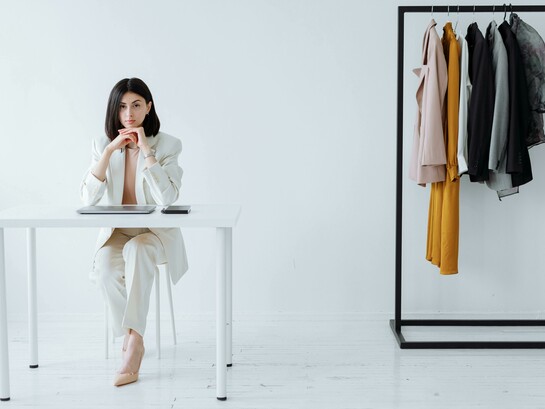 A stylist sitting at a desk in a fashion store, preparing looks and assisting clients