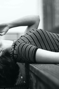 A woman lying down on the street smoking a cigarette